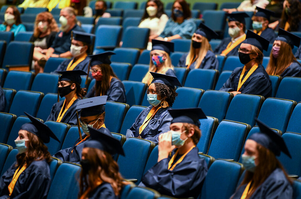 Graduates and guests listen to a videotaped address by graduate William Henderson